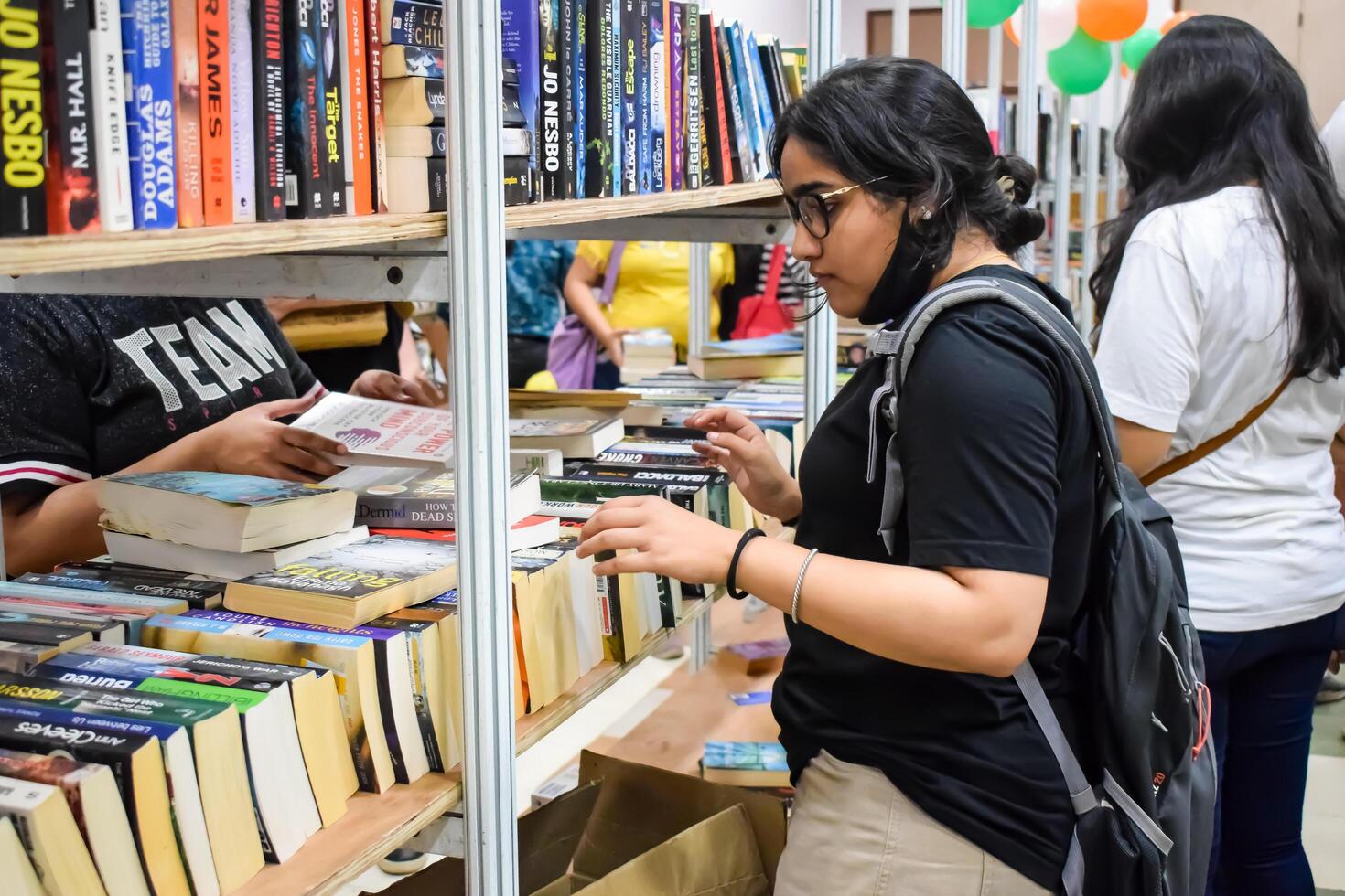 Delhi, India, September 09 2023 - Various age group people reading variety of Books on shelf inside a book-stall at Delhi International Book Fair, Selection of books on display in Annual Book Fair photo