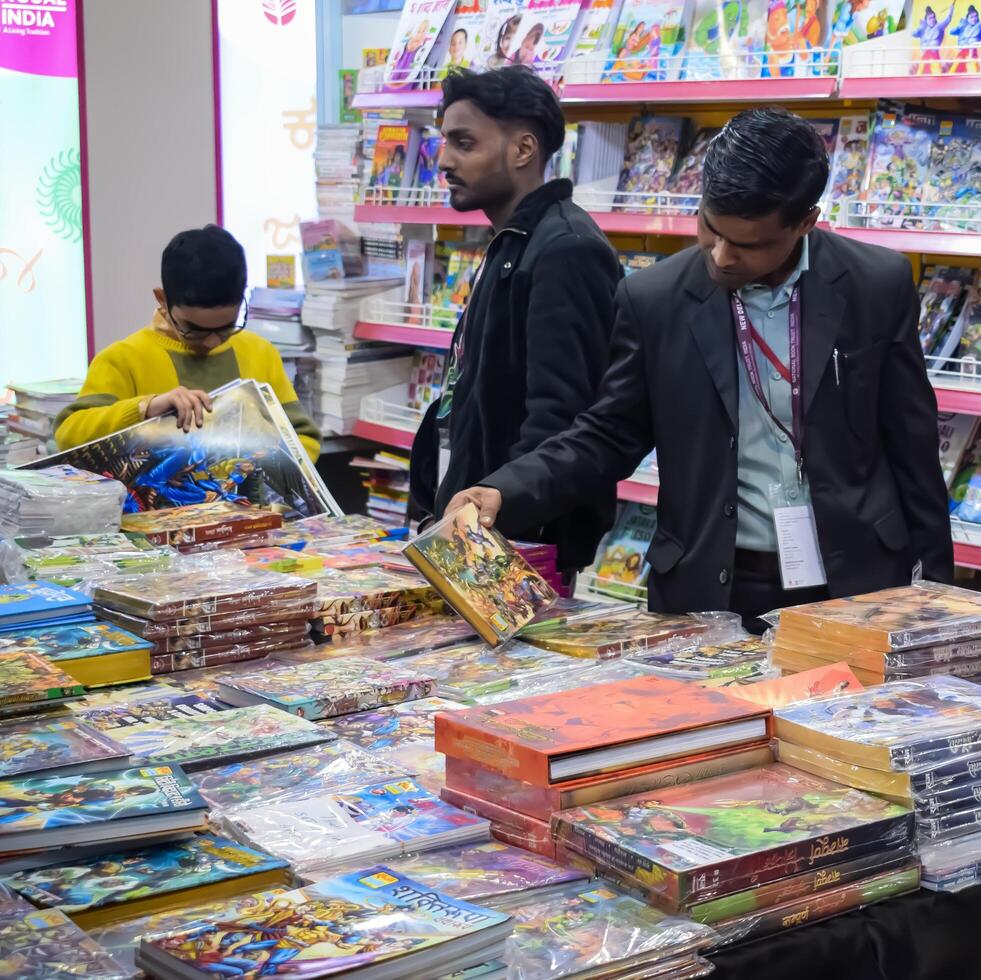 Delhi, India, February 17 2024 - Various age group people reading variety of Books on shelf inside a book-stall at Delhi International Book Fair, Books in Annual Book Fair at Bharat Mandapam complex photo