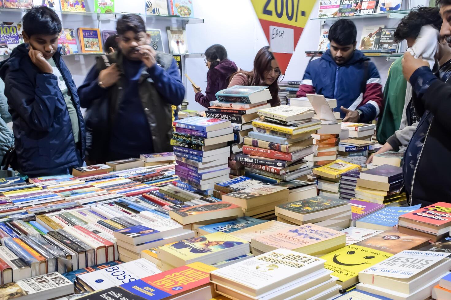 Delhi, India, February 17 2024 - Various age group people reading variety of Books on shelf inside a book-stall at Delhi International Book Fair, Books in Annual Book Fair at Bharat Mandapam complex photo