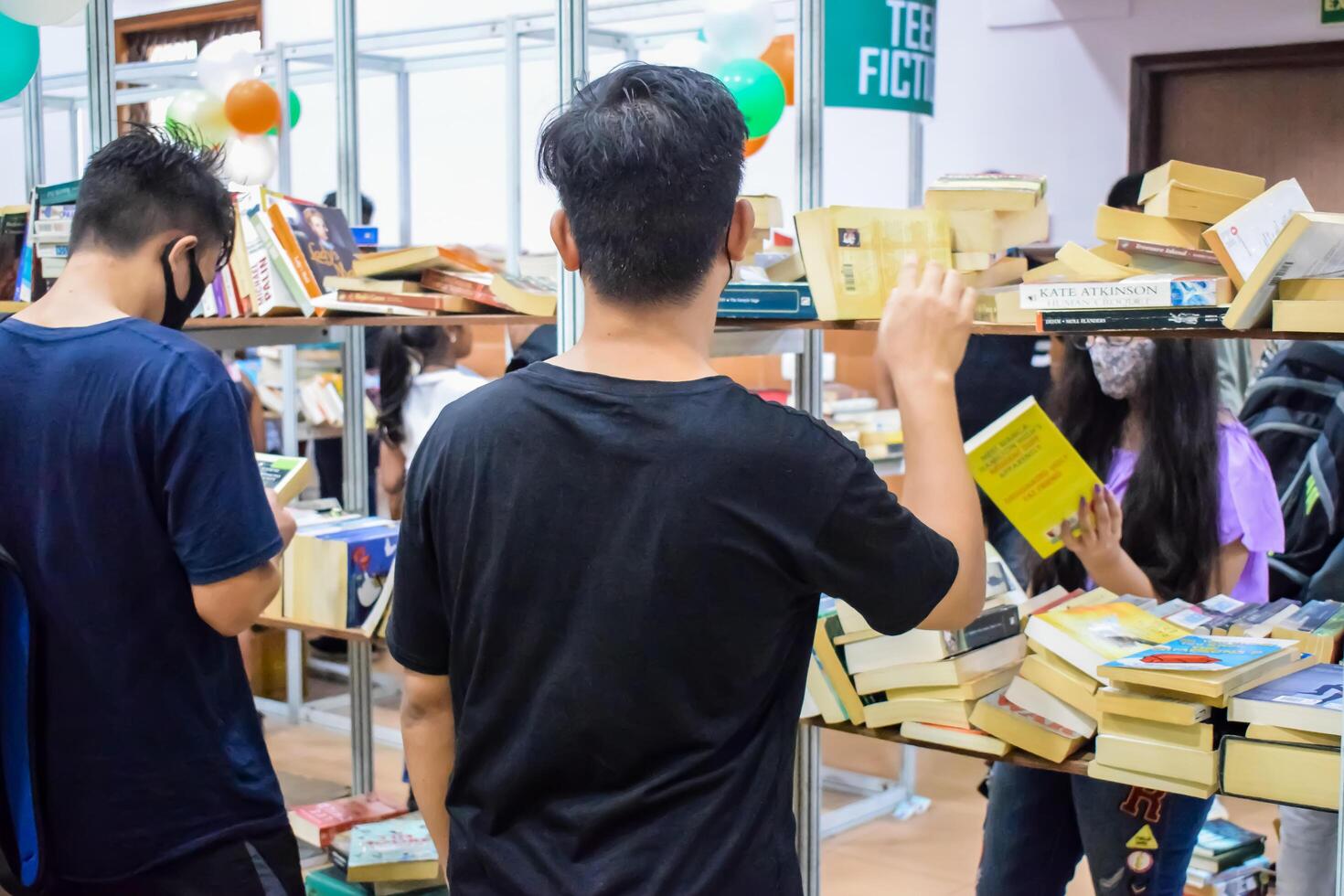 Delhi, India, September 09 2023 - Various age group people reading variety of Books on shelf inside a book-stall at Delhi International Book Fair, Selection of books on display in Annual Book Fair photo