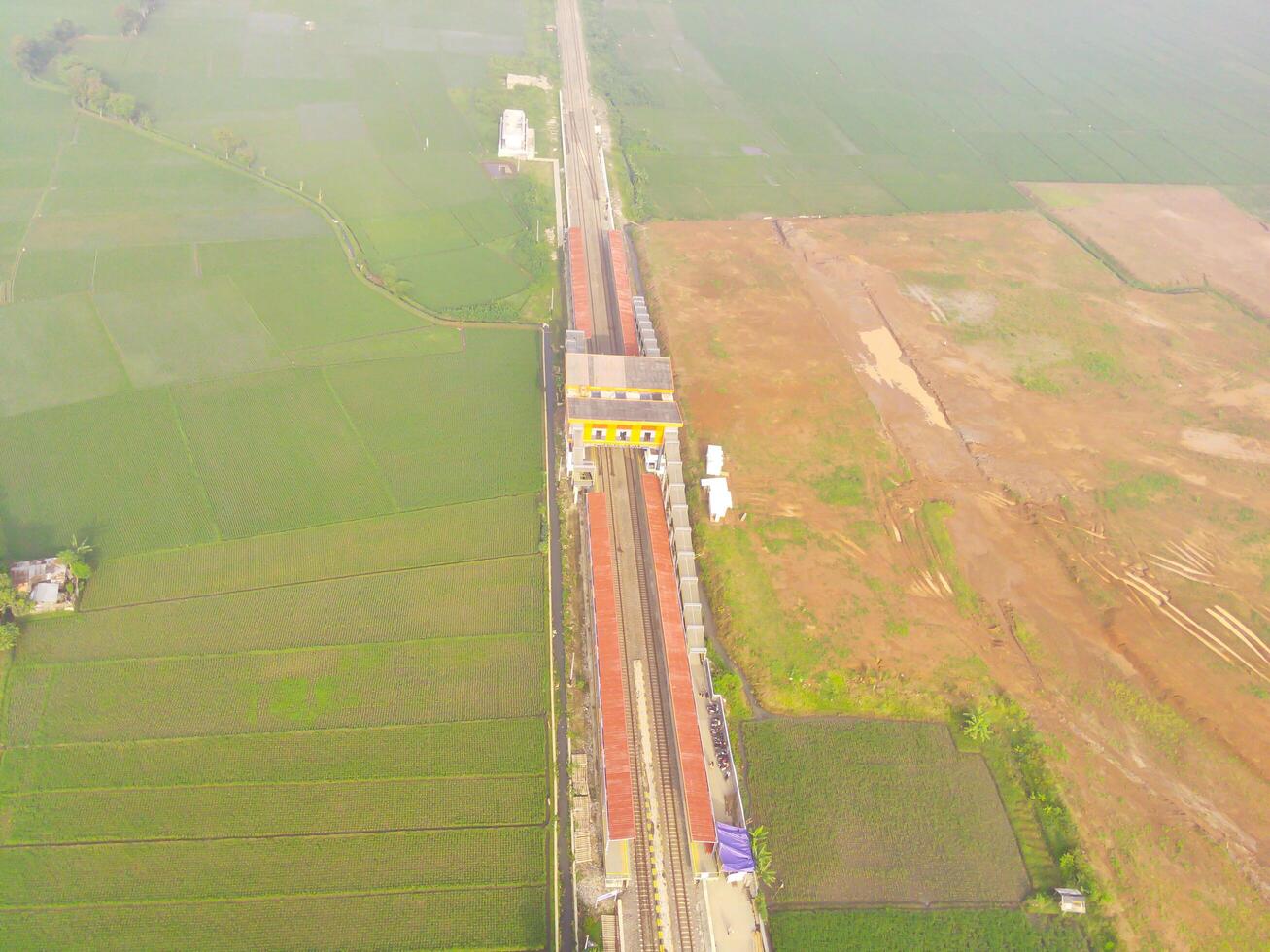 brumoso ver de el ferrocarril línea. aéreo ver de tren pista y estación en rancaekek, Bandung - Indonesia. natural condiciones. arriba. público transporte. Disparo en zumbido volador 100 metros foto