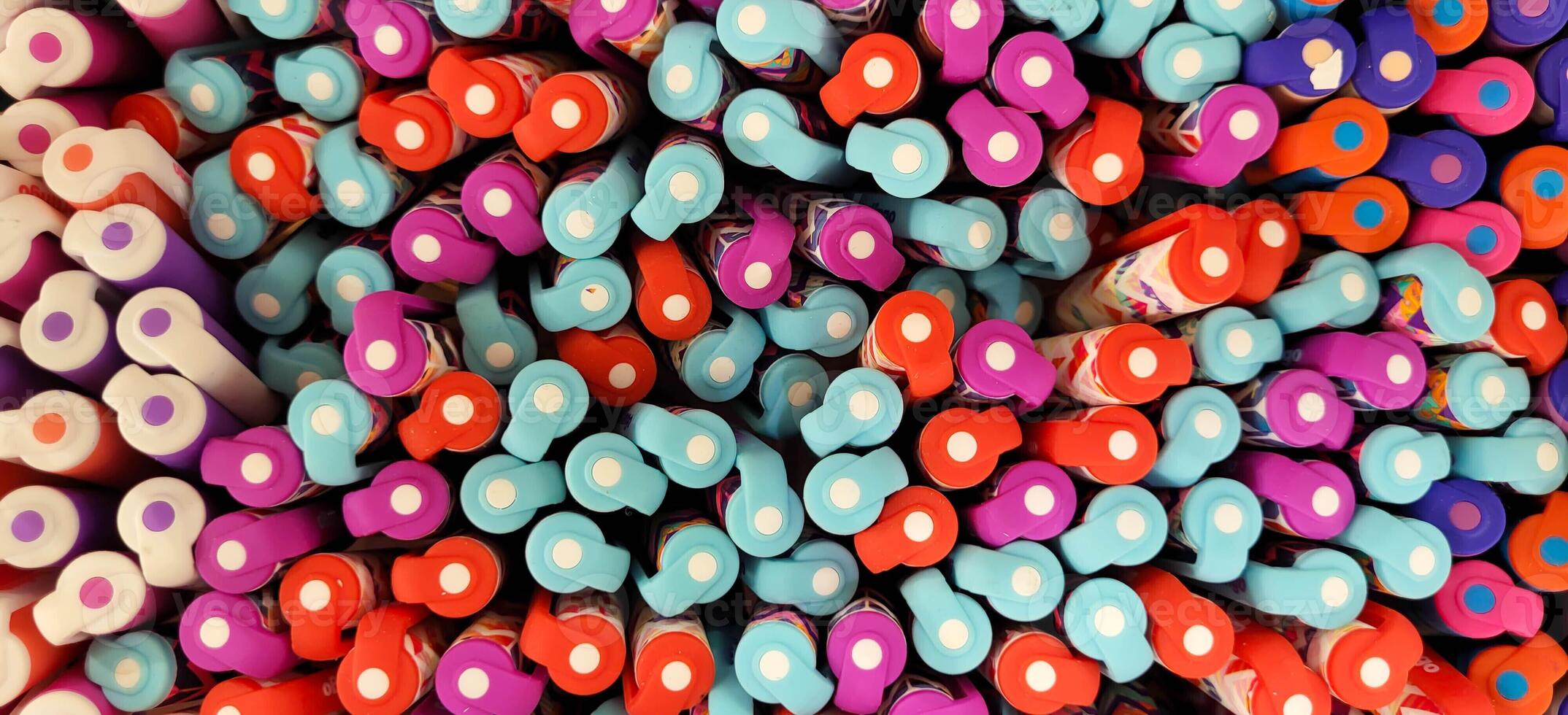 Abstract background of multicolored caps of plastic pens. A set of several liners, markers and colored markers of different colors, top view photo