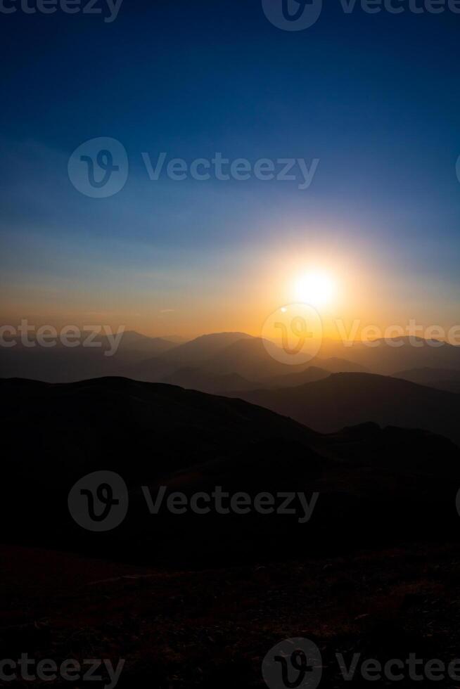 puesta de sol terminado el colinas y silueta de el sierras. foto