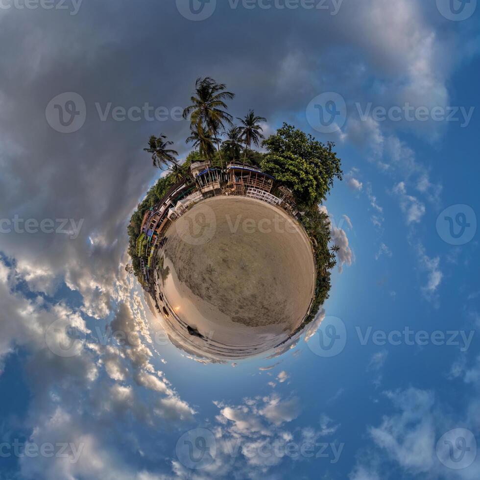 coconut trees in jungle in Indian tropic village on sea shore on little planet in blue sky, transformation of spherical 360 panorama. Spherical abstract view with curvature of space. photo