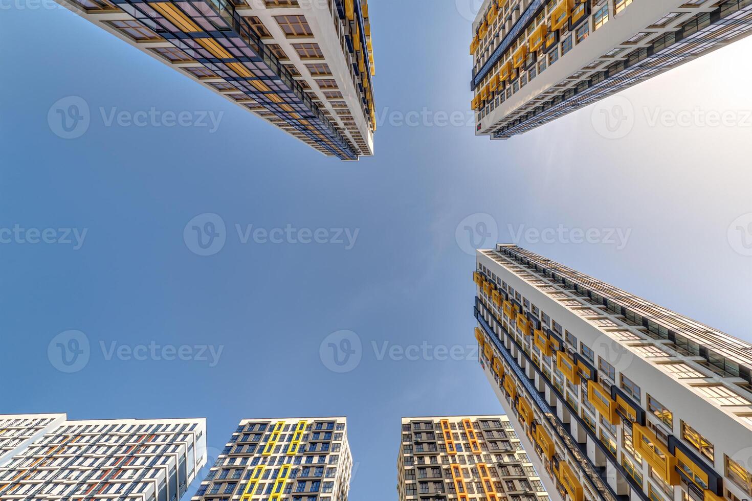 view from below into blue sky with clouds of large modern skyscraper residential complex photo