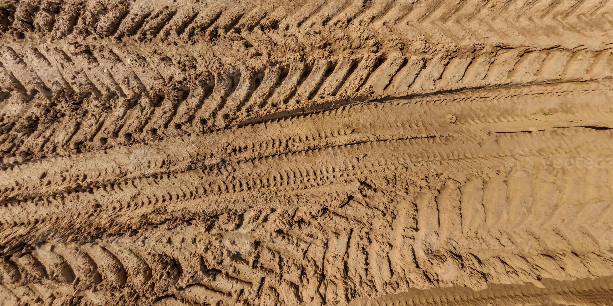 view from above on texture of wet muddy road with tractor tire tracks in countryside photo