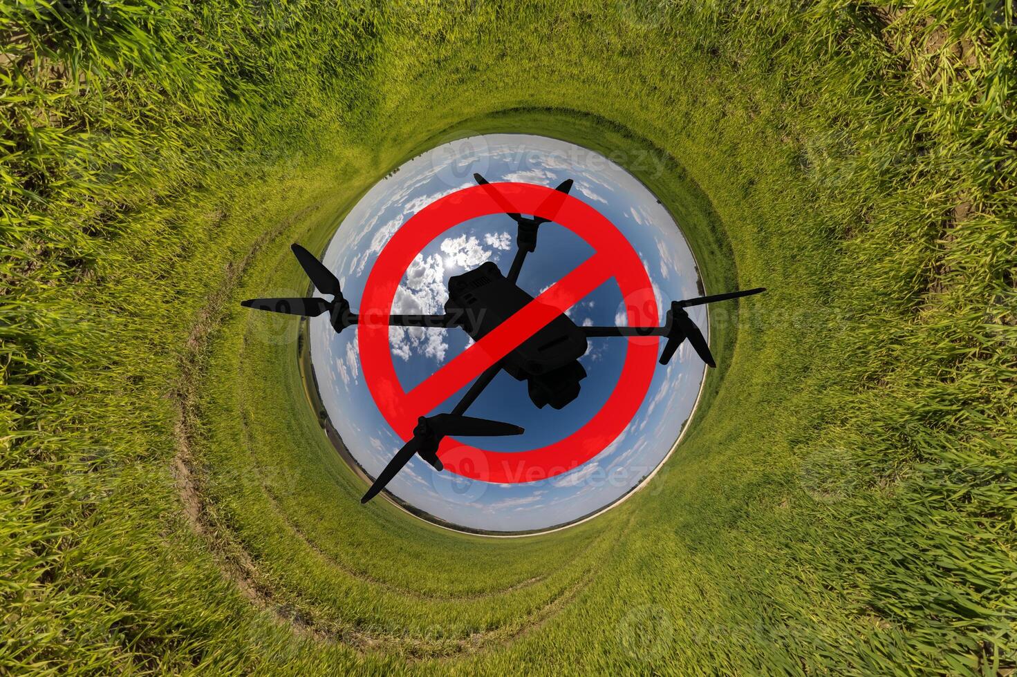 No drone zone sign concept for banning the use of drones in airspace. drone silhouette in red circle with crossed out stripe on blue hole sphere little planet inside grass round frame background photo