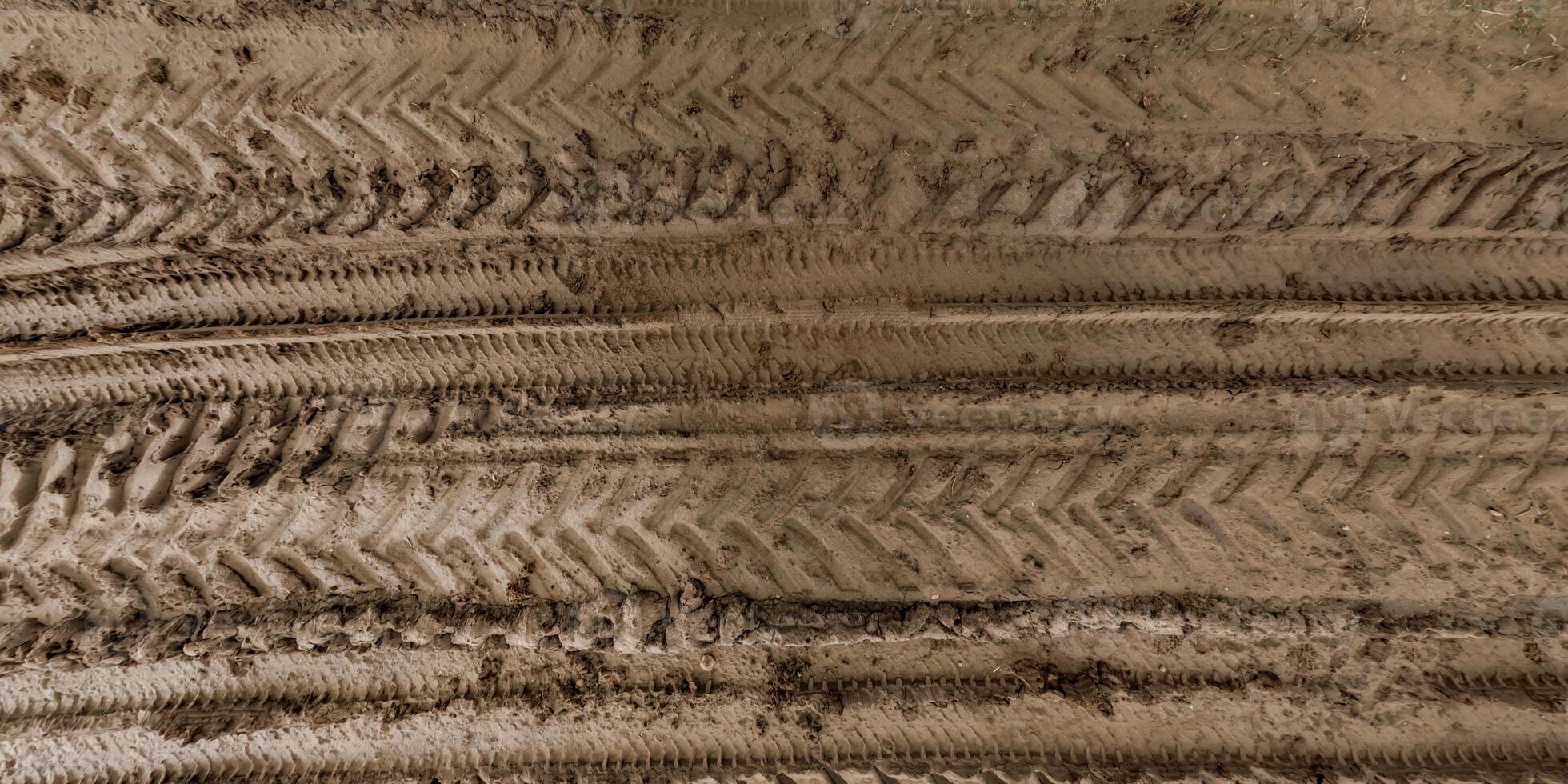 view from above on texture of wet muddy road with puddle and tractor tire tracks in countryside photo