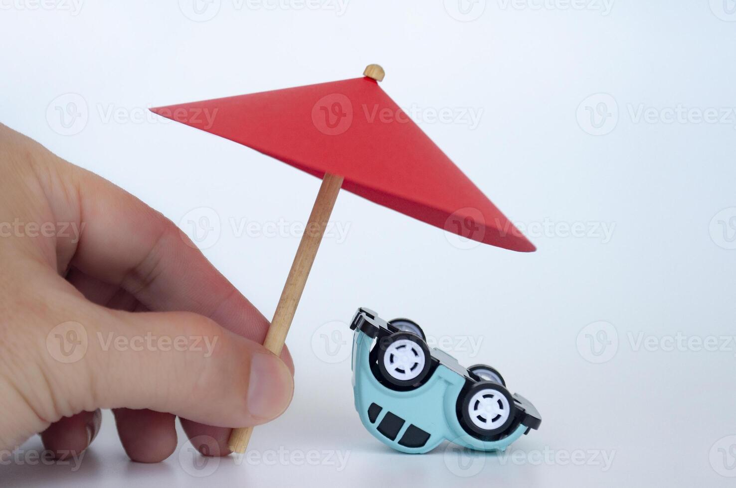 Red toy umbrella and upside down blue toy car on white background photo