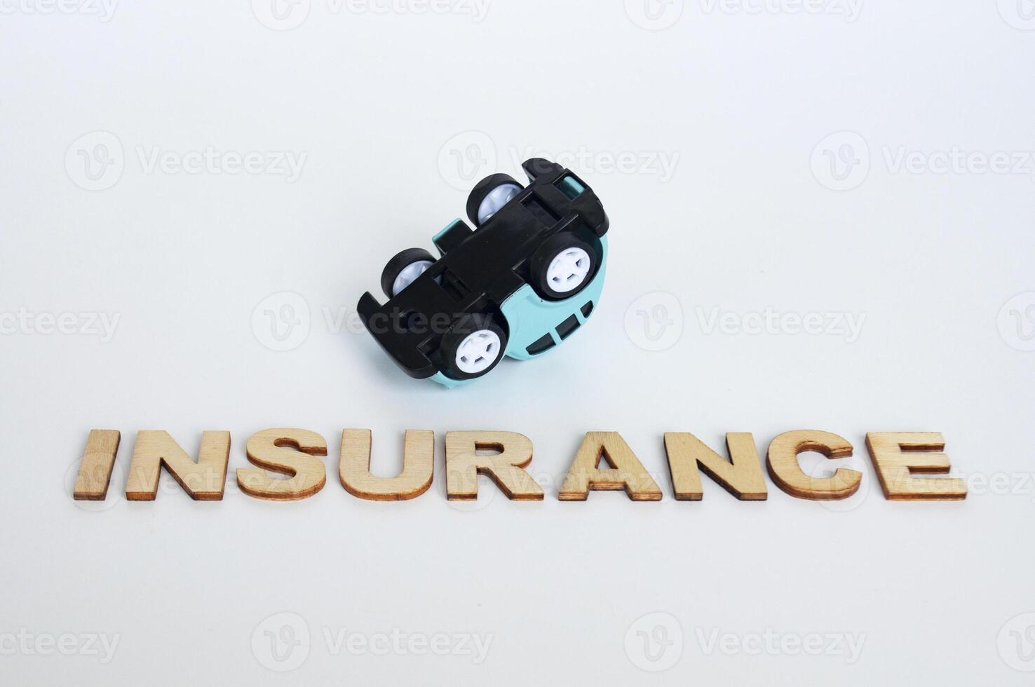 Insurance text with upside down toy car background. Car insurance concept photo
