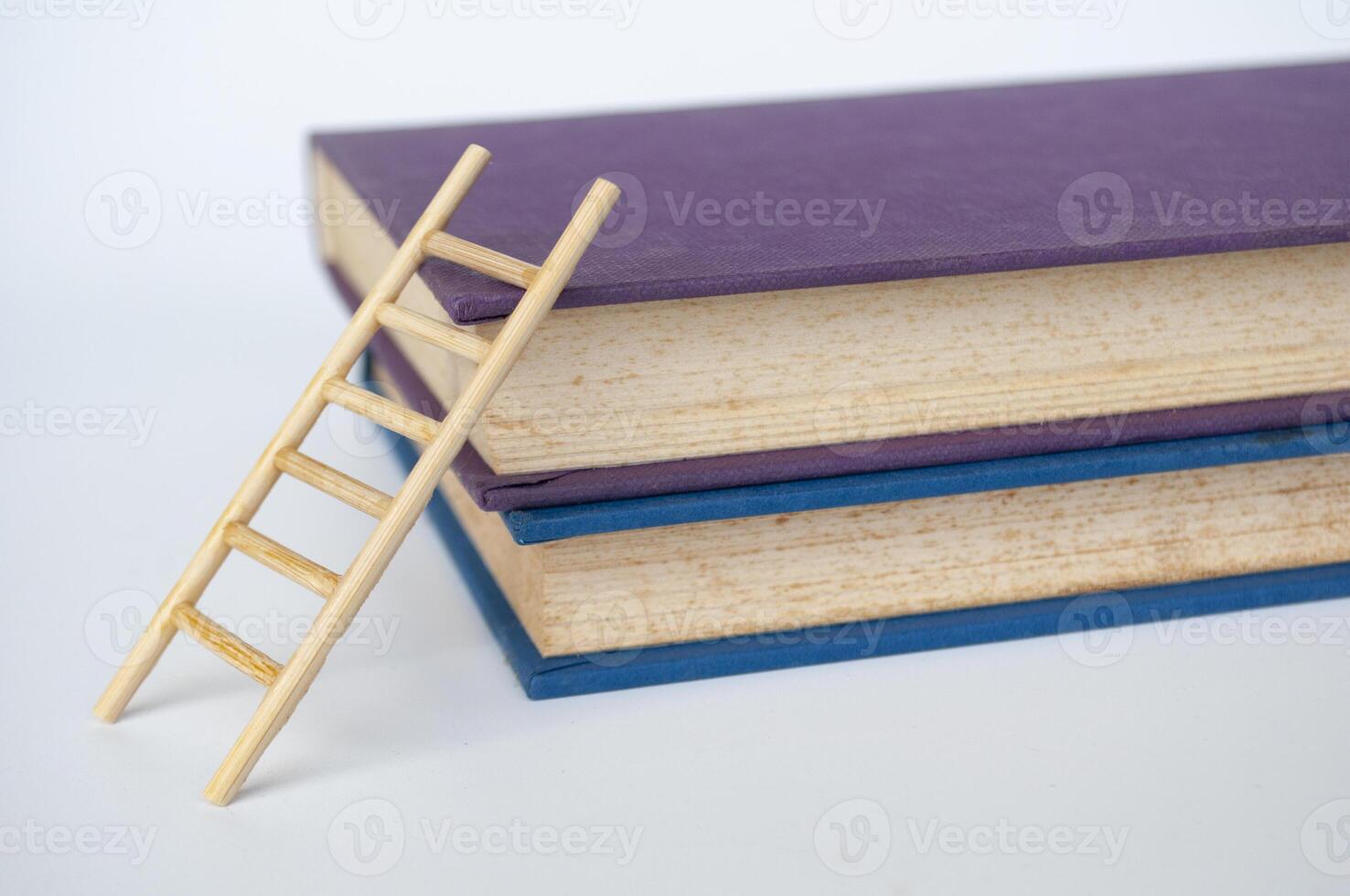Toy wooden ladder next to books with white background. Learning concept photo