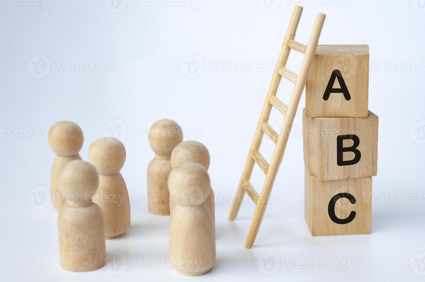 ABC text on wooden cubes with ladder and doll figures on white background. Knowledge concept photo