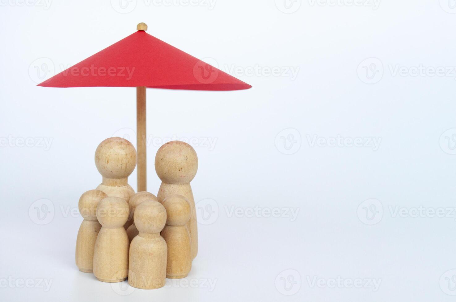 Red toy umbrella and wooden family doll figures a white background. Life insurance coverage concept photo