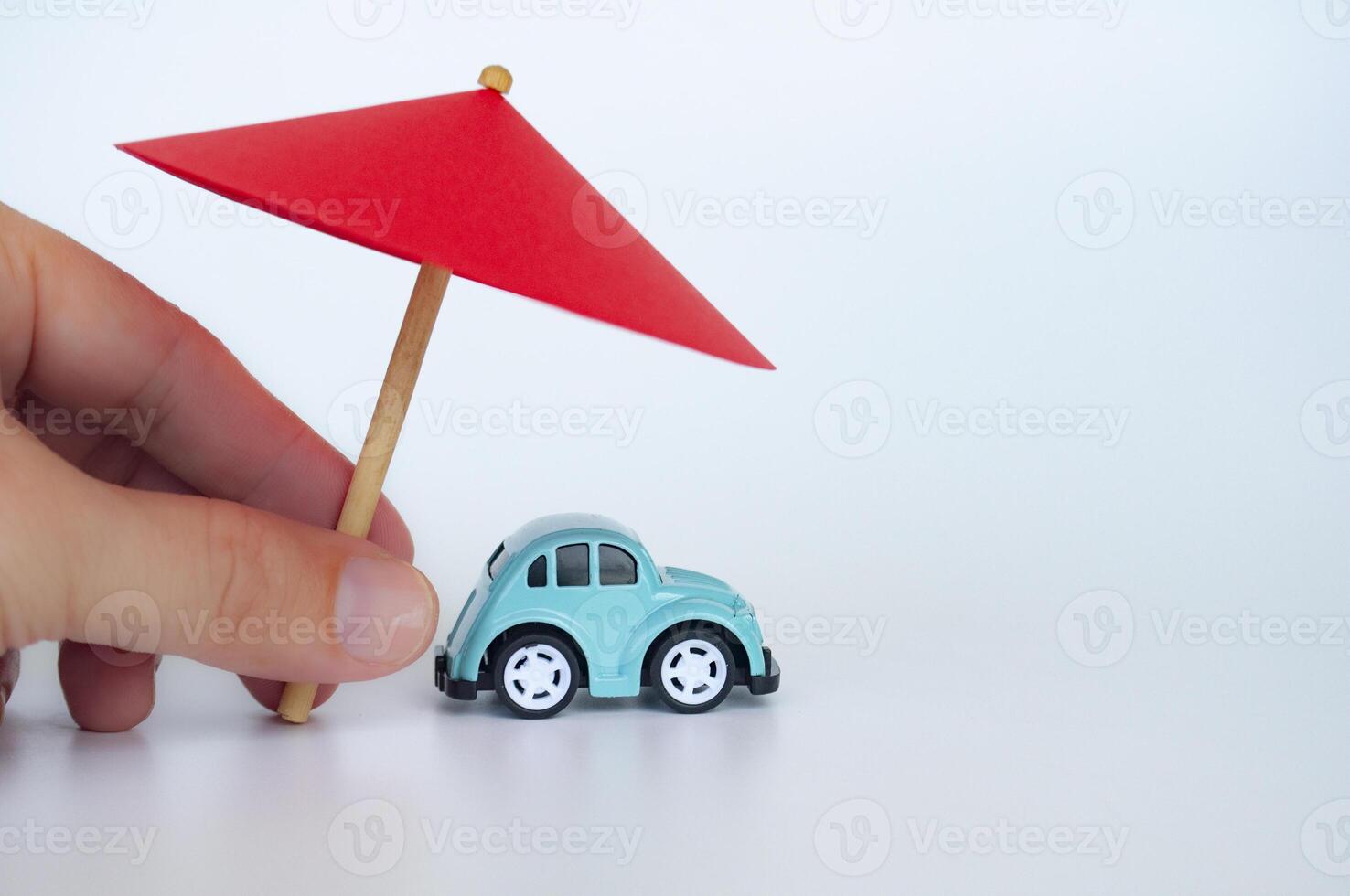 Red toy umbrella and blue toy care on white background. Car insurance coverage concept photo