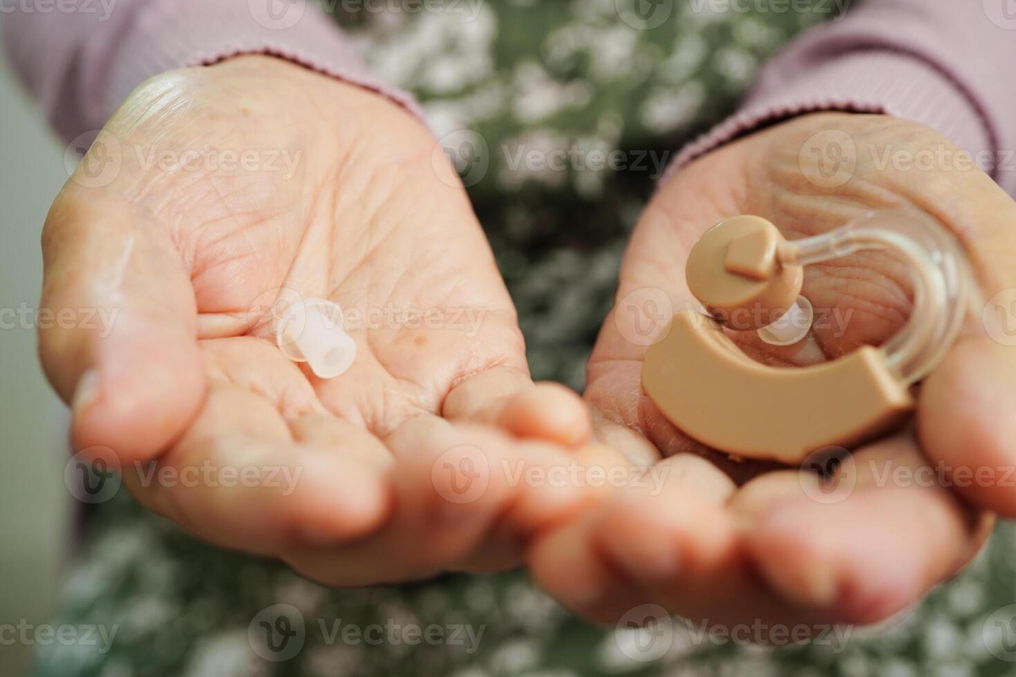 Asian senior woman patient using hearing aid in ear to reduce hearing loss problem. photo
