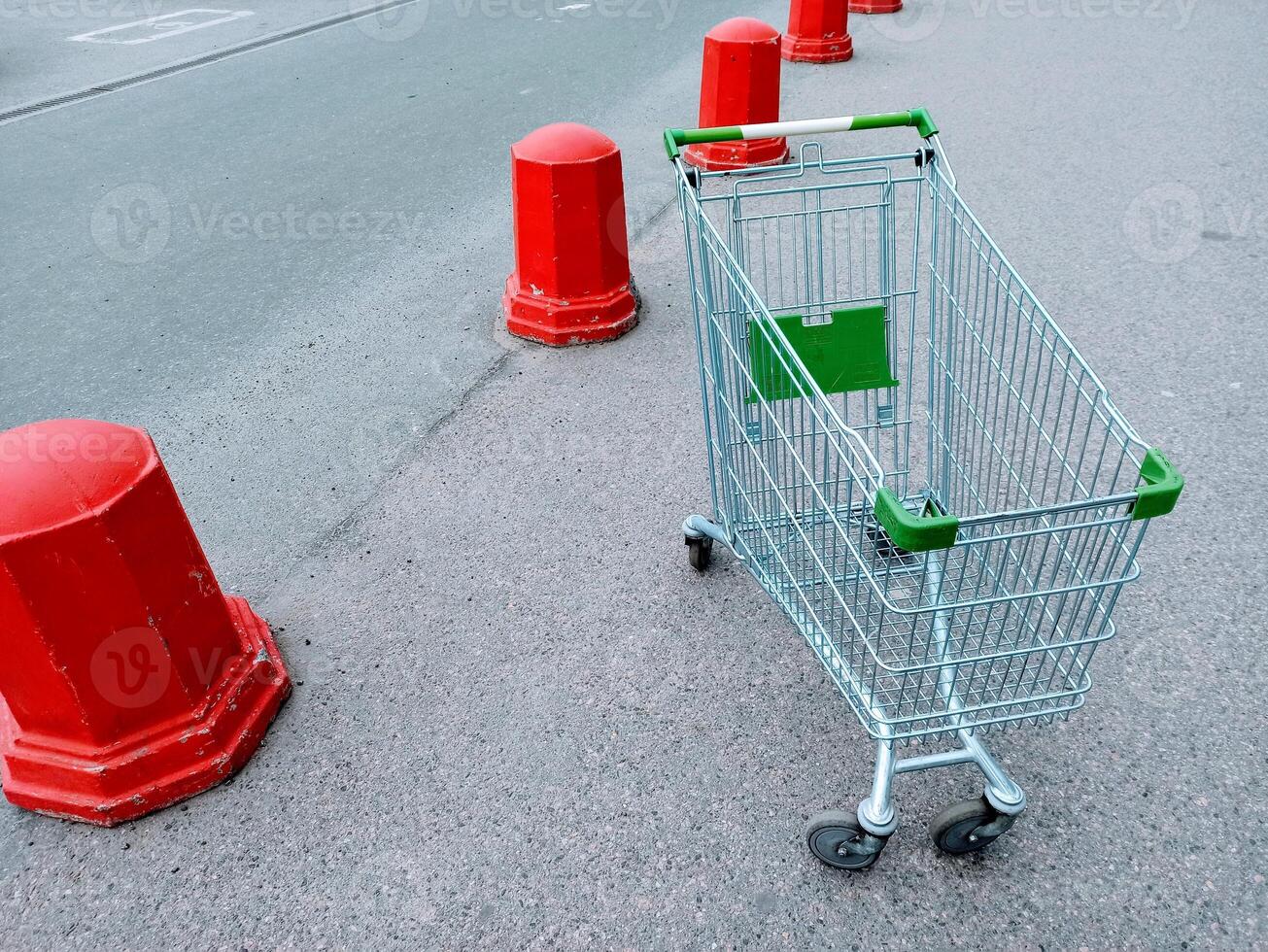 Empty shopping cart on the road with red traffic cones in the background photo