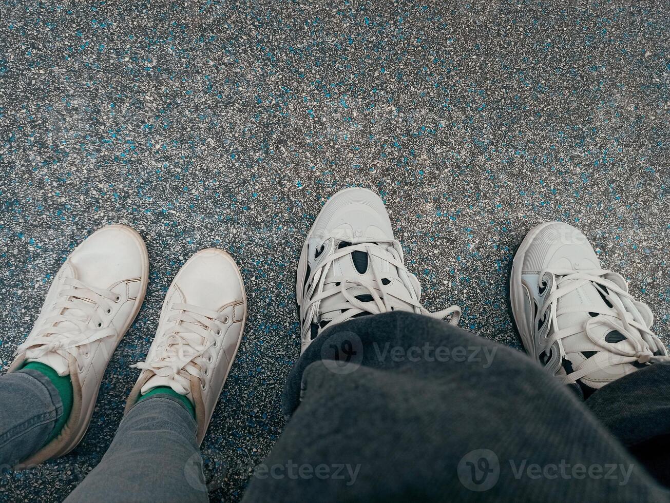 Selfie of man and woman legs in white sneakers standing on the floor photo