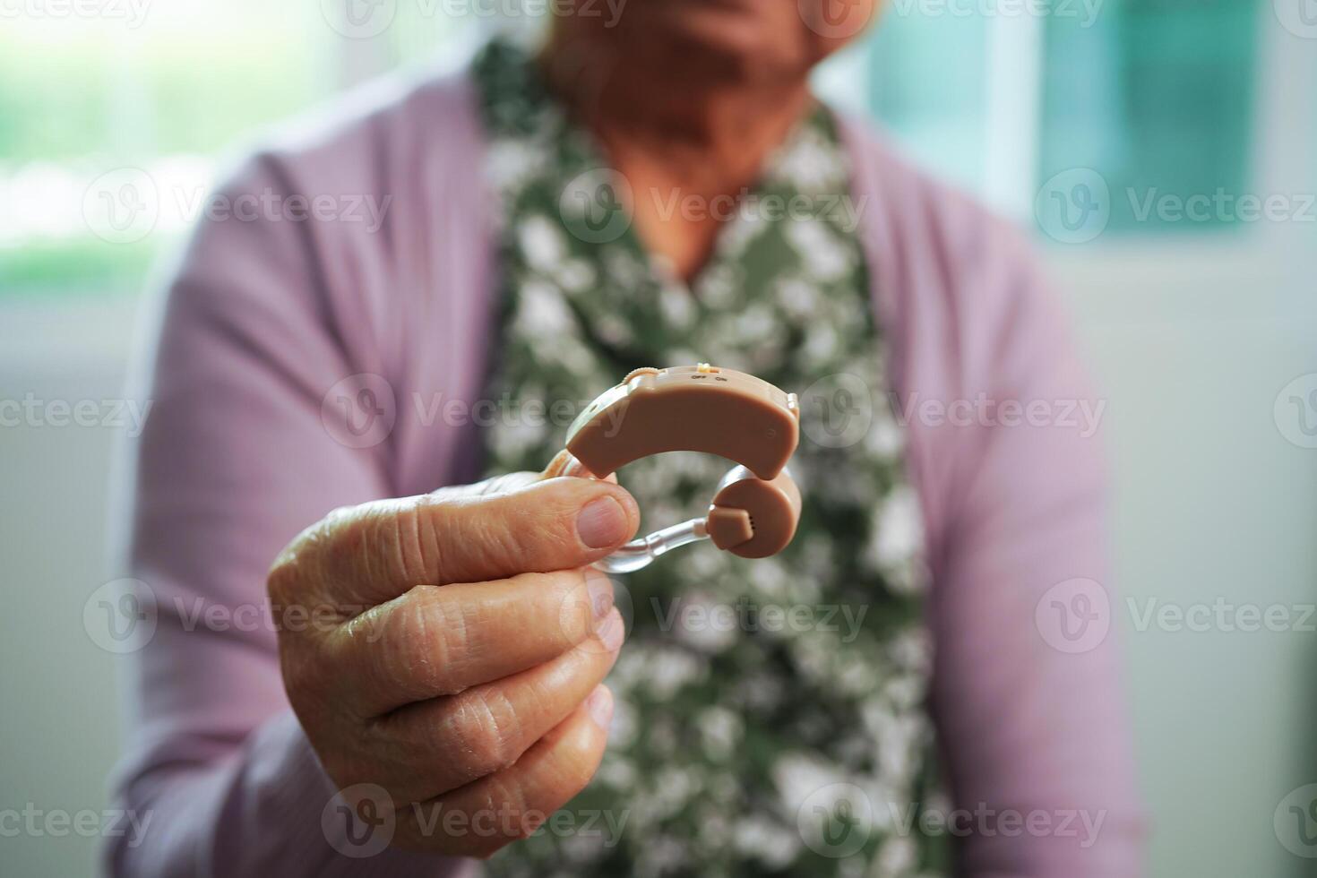 Asian senior woman patient using hearing aid in ear to reduce hearing loss problem. photo