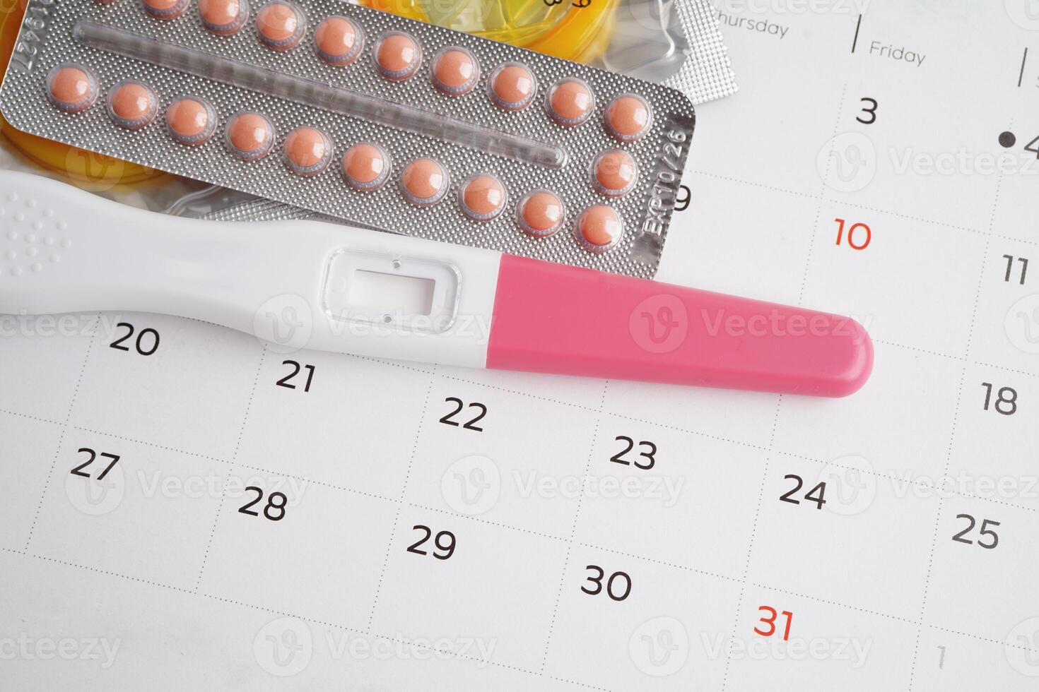 Pregnancy test with birth control pills and condom for female on calendar, ovulation day. photo