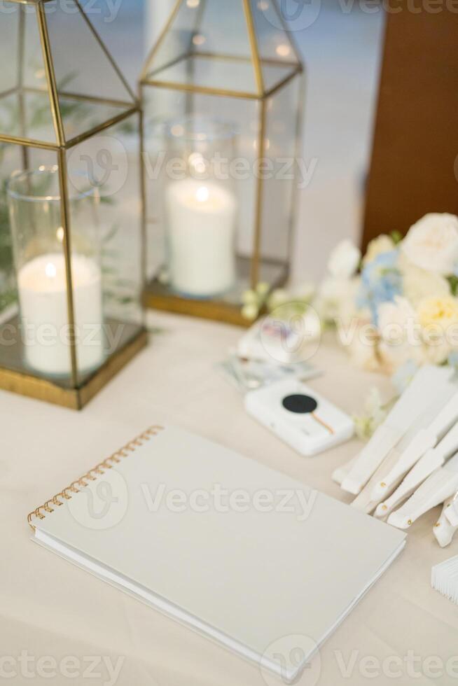 Lighted candles in glass lamps stand on the table next to a notepad photo