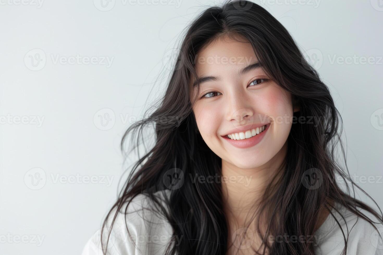 Asian woman with long hair is smiling and looking at the camera photo