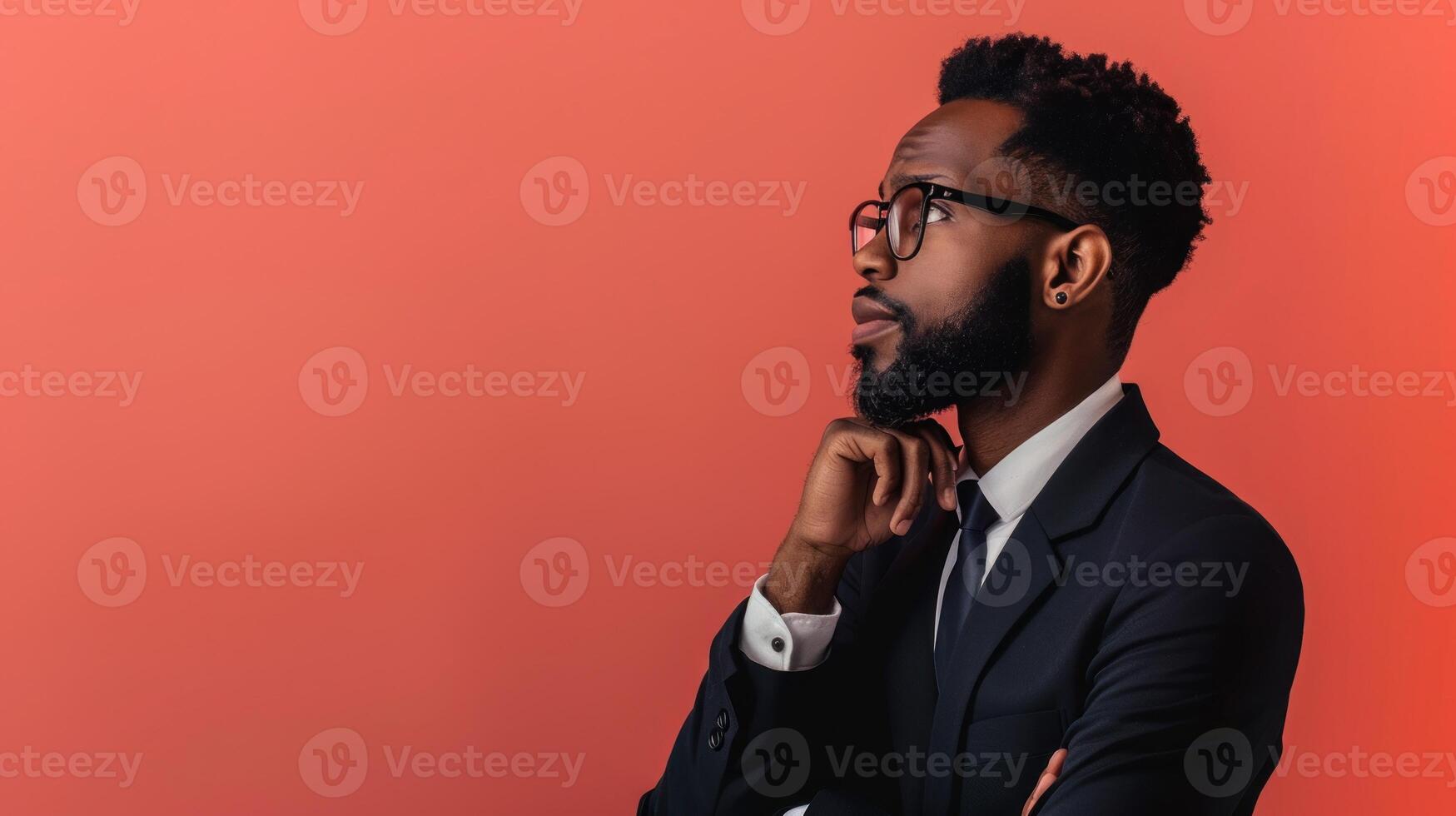A man with a beard and a white shirt is standing in front of a red wall photo