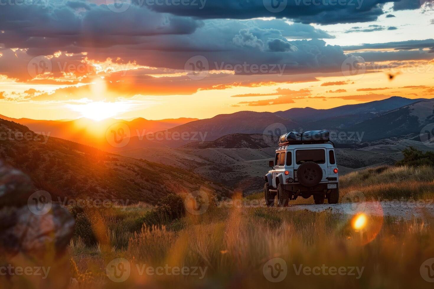 A car is driving down a road with a beautiful sunset in the background photo