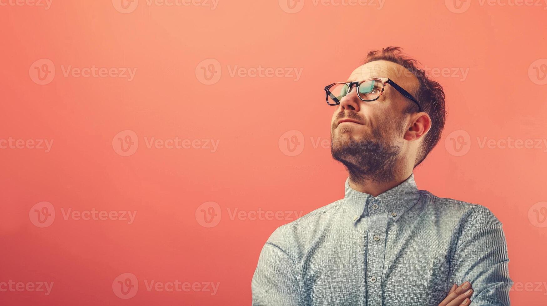 A man with a beard and a white shirt is standing in front of a red wall photo