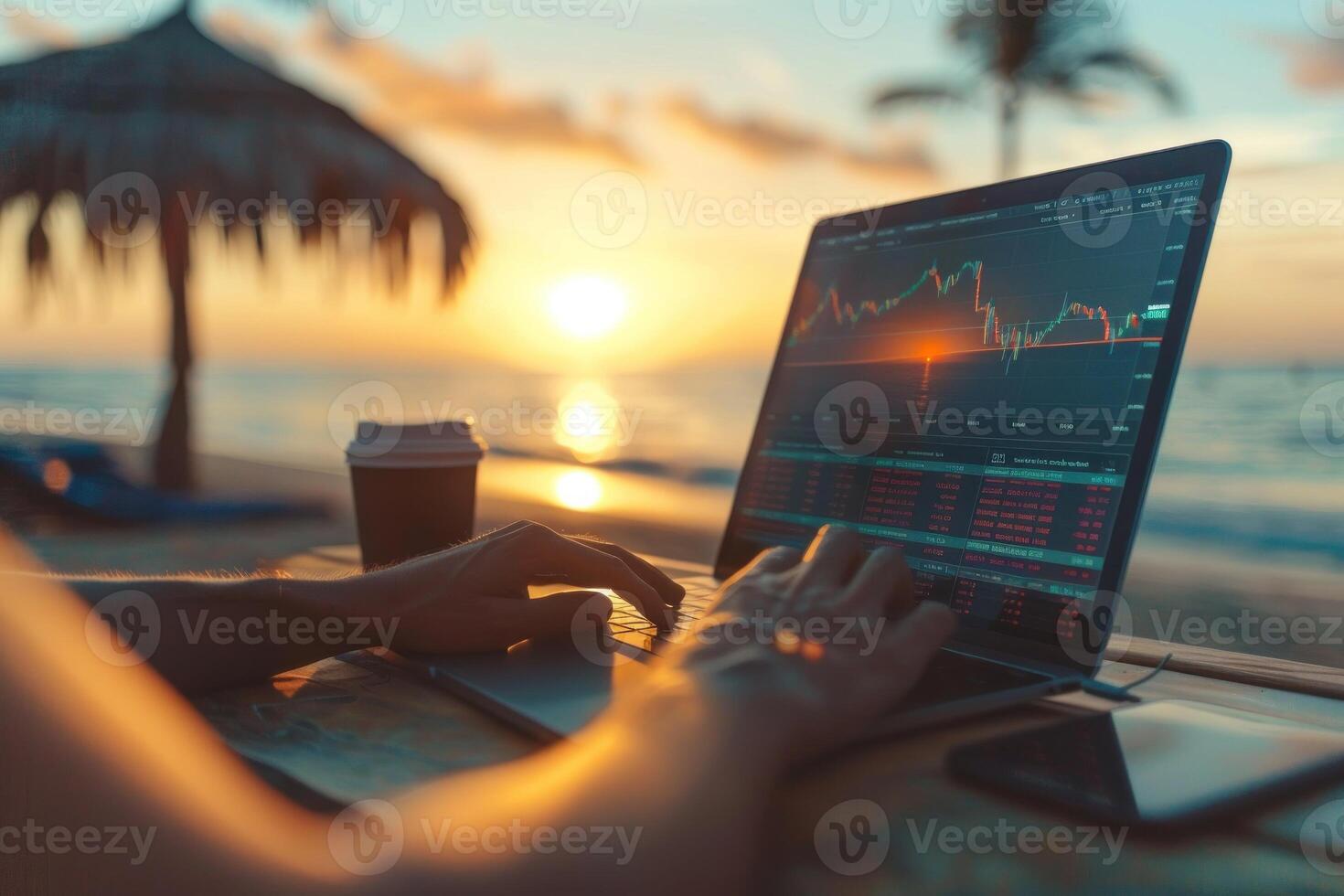 A person is sitting on a beach with a laptop open, working on a financial report photo