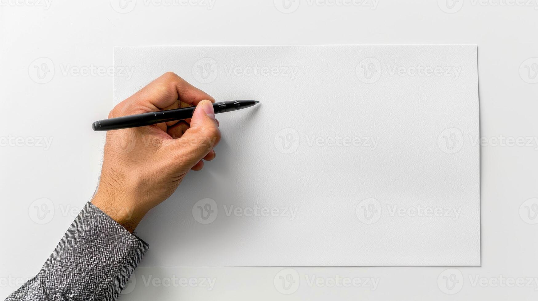 A hand is writing on a blank piece of paper with a pen photo