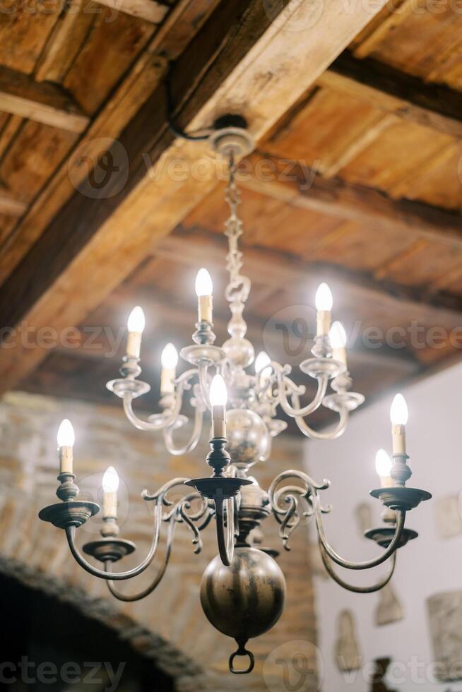 bronce brillante candelabro con esferas y vela lamparas cuelga desde un de madera techo foto