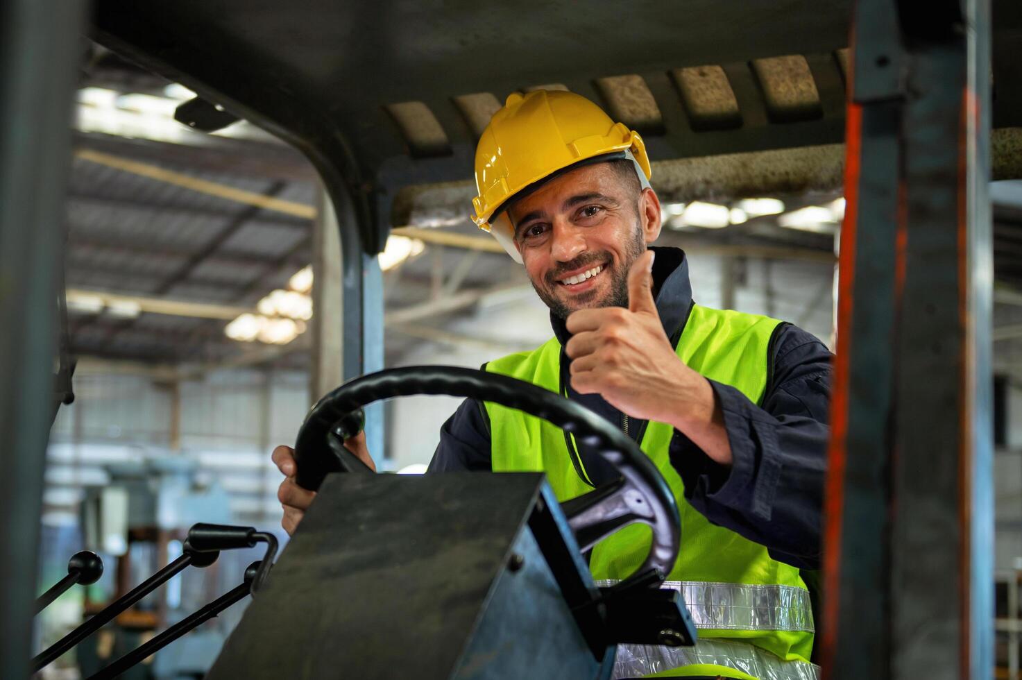 forklift driver sits in his vehicle in a warehouse and gives a thumbs up to show confidence in his work photo