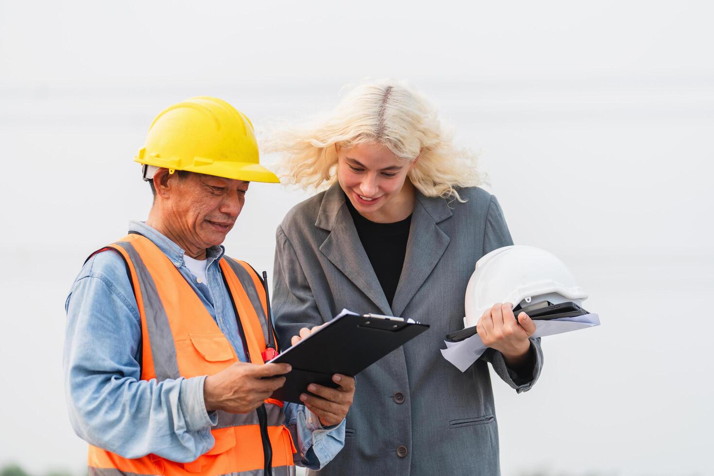 man and a woman are standing next to each other, looking at a clipboard photo