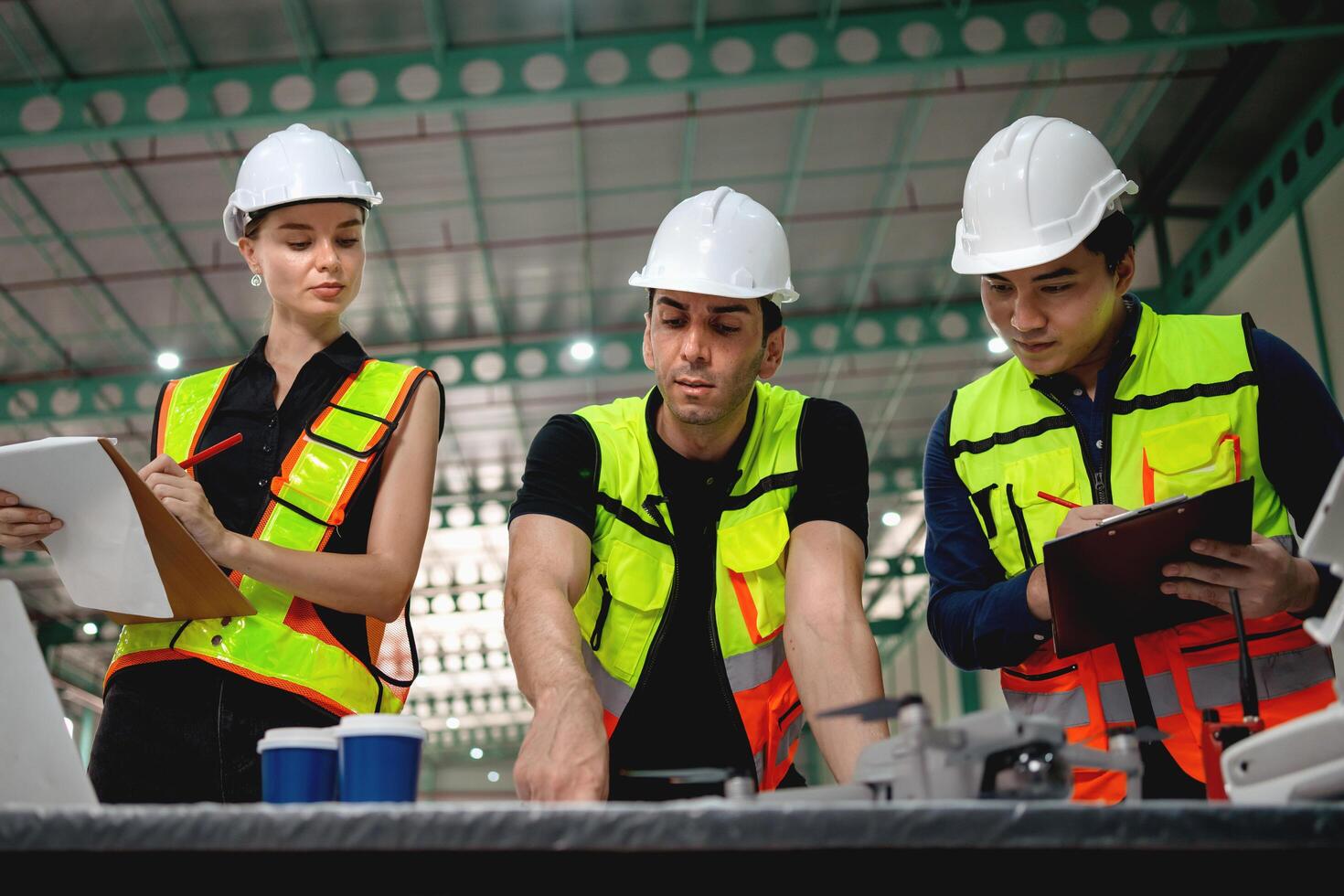 Three construction workers are standing around a table, looking at a laptop photo