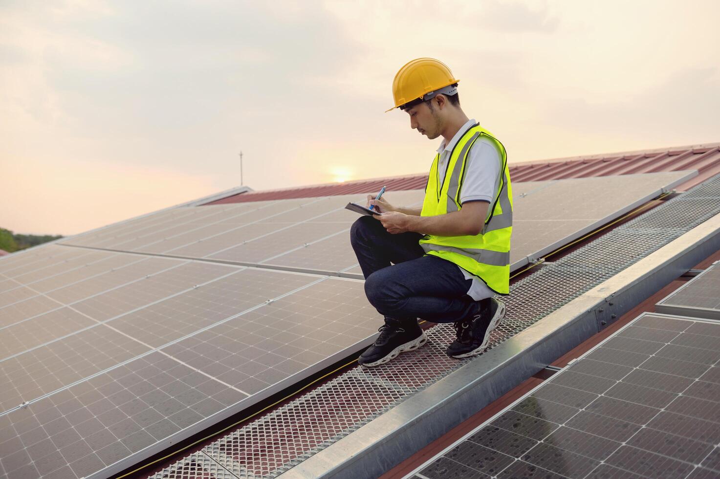 hombre en un amarillo chaleco es trabajando en un solar panel foto