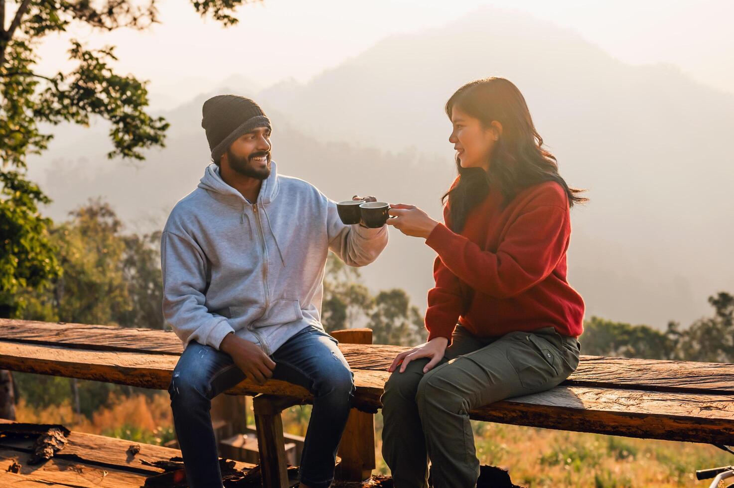 man and woman are sitting on a wooden bench, smiling at each other photo