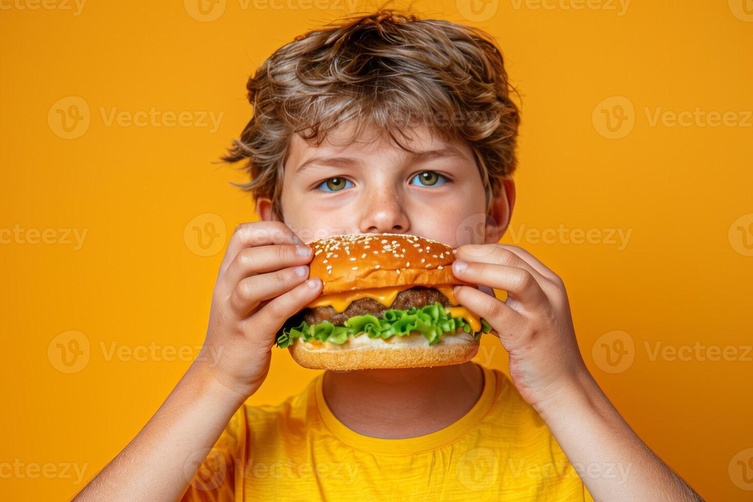 Young boy savoring hamburger against pastel backdrop with ample space for text placement photo