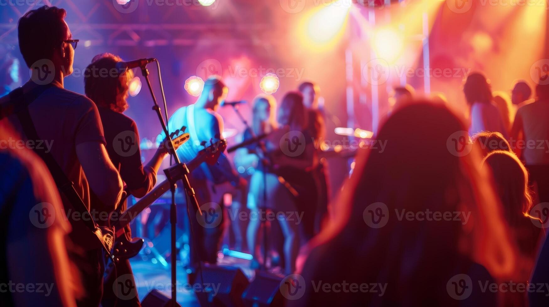 A live band playing on stage with a crowd of people dancing and swaying to the music photo