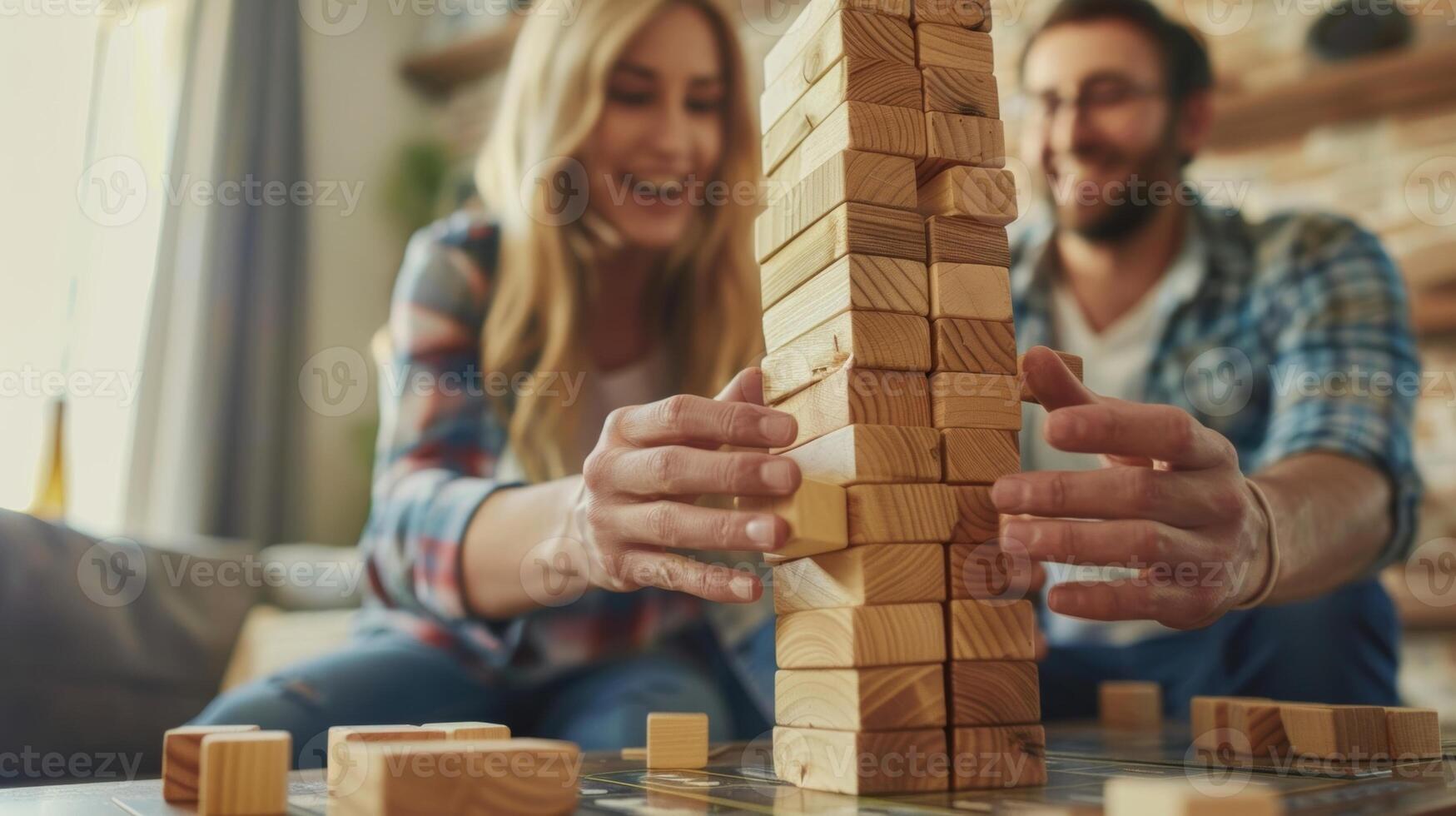 A game of Jenga is set up on a coffee table the couple laughing as they carefully remove pieces with steady hands photo