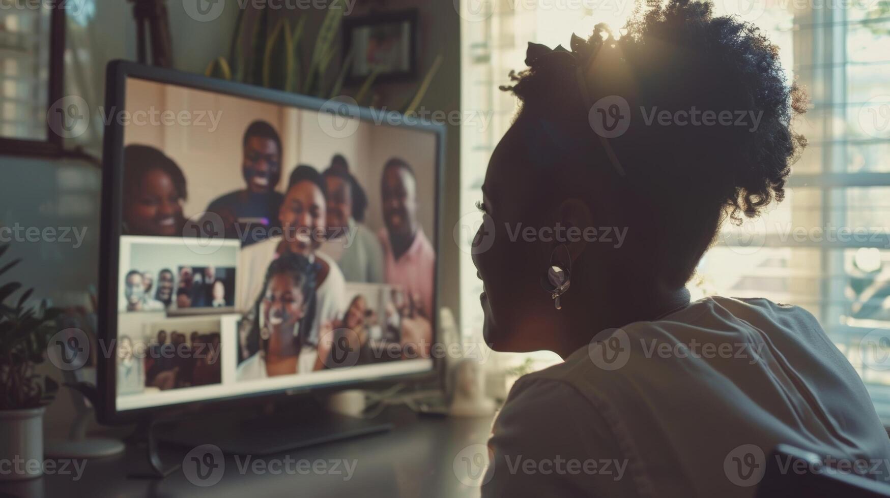 A person sitting at their desk smiling while looking at a framed photo of themselves surrounded by their loved ones taken at a sobriety celebration for their fifth year of sobriety