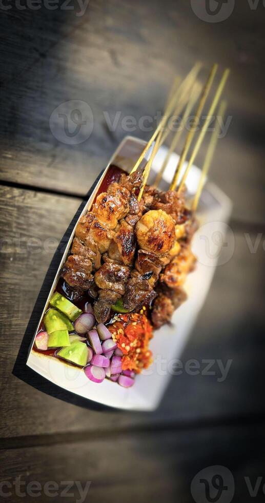 Lamb grilled satay served with barbecue savory sauce and pickled onion, chili and cucumber, selective focus photo