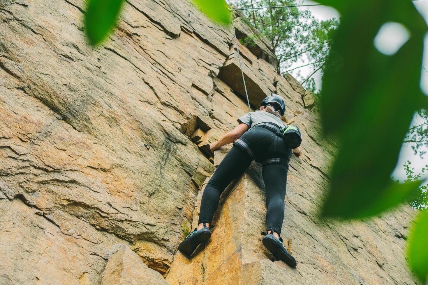 Young athletic woman in equipment doing rock climbing outdoors. Training area for outdoor activities. Extreme sport. photo