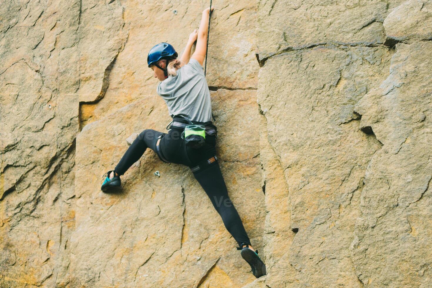 Young athletic woman in equipment doing rock climbing outdoors. Training area for outdoor activities. Extreme sport. photo