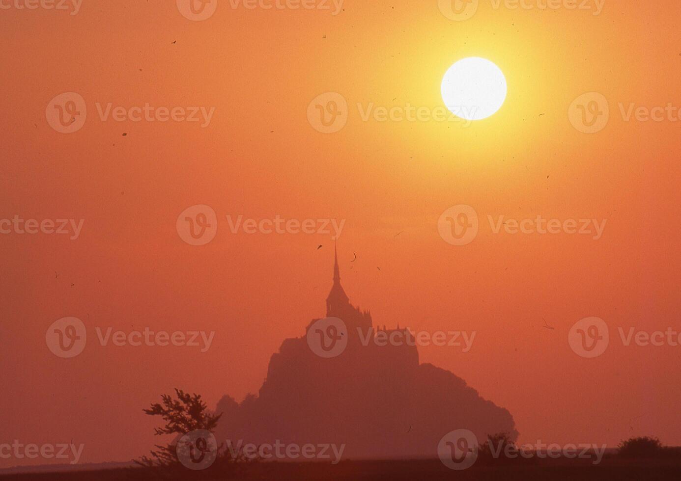 the sun is setting behind a mountain photo