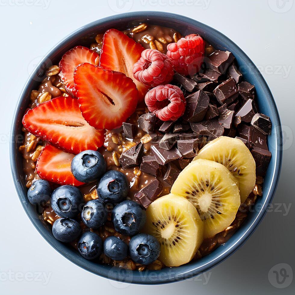 Chocolate oatmeal with a variety of fruits in blue bowl isolated on white background. Chocolate oatmeal with strawberries, blueberries and bananas top view photo