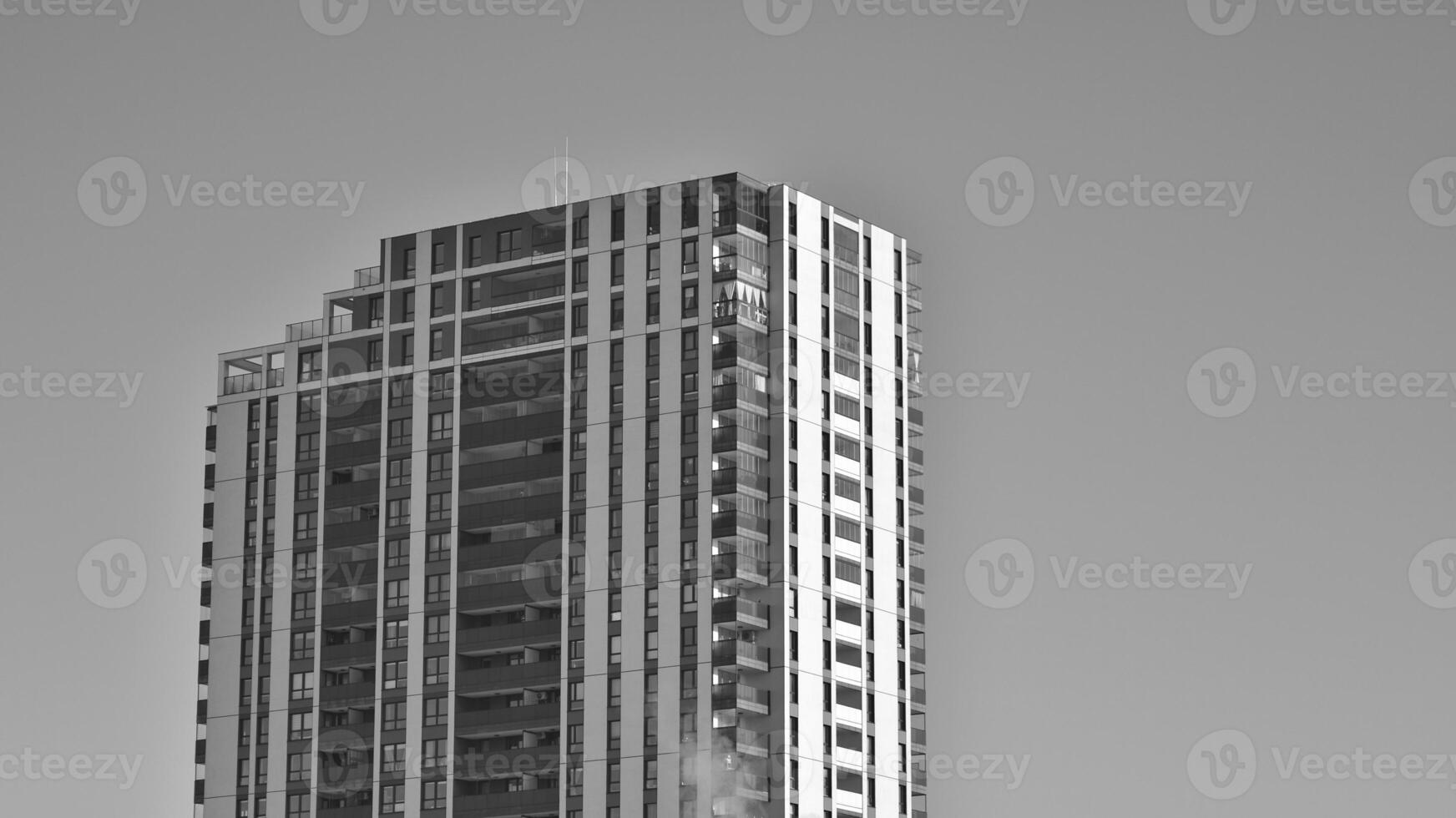Fragment of the building's facade with windows and balconies. Modern apartment buildings on a sunny day. Facade of a modern residential building. Black and white. photo