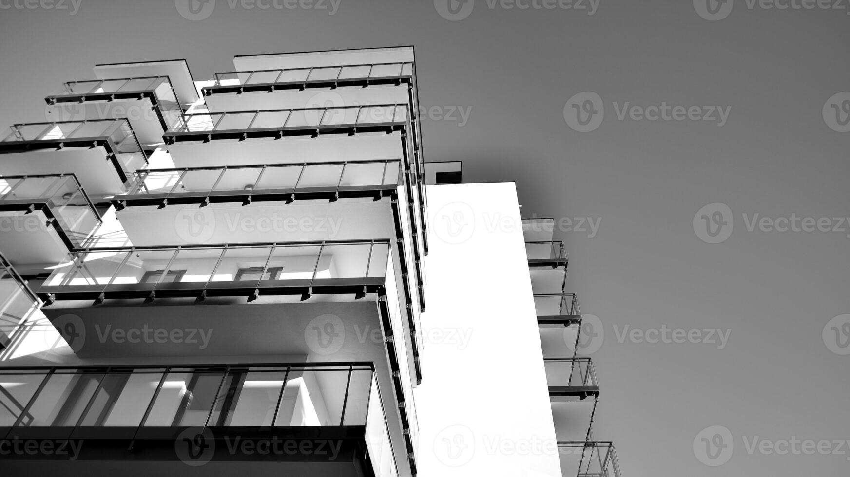 Fragment of a facade of a building with windows and balconies. Modern apartment buildings on a sunny day. Facade of a modern apartment building. Black and white. photo