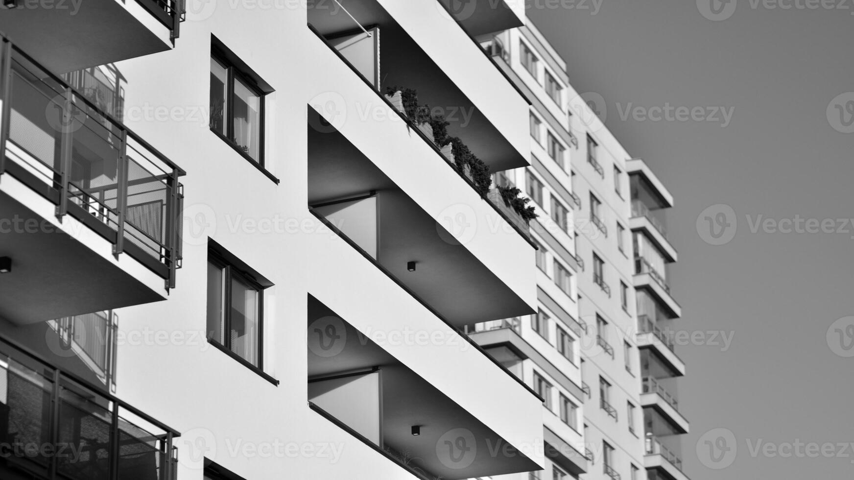 Fragment of the building's facade with windows and balconies. Modern apartment buildings on a sunny day. Facade of a modern residential building. Black and white. photo