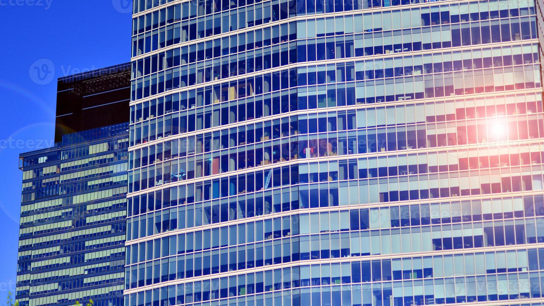 Glass building with transparent facade of the building and blue sky. Structural glass wall reflecting blue sky. Abstract modern architecture fragment. Contemporary architectural background. photo