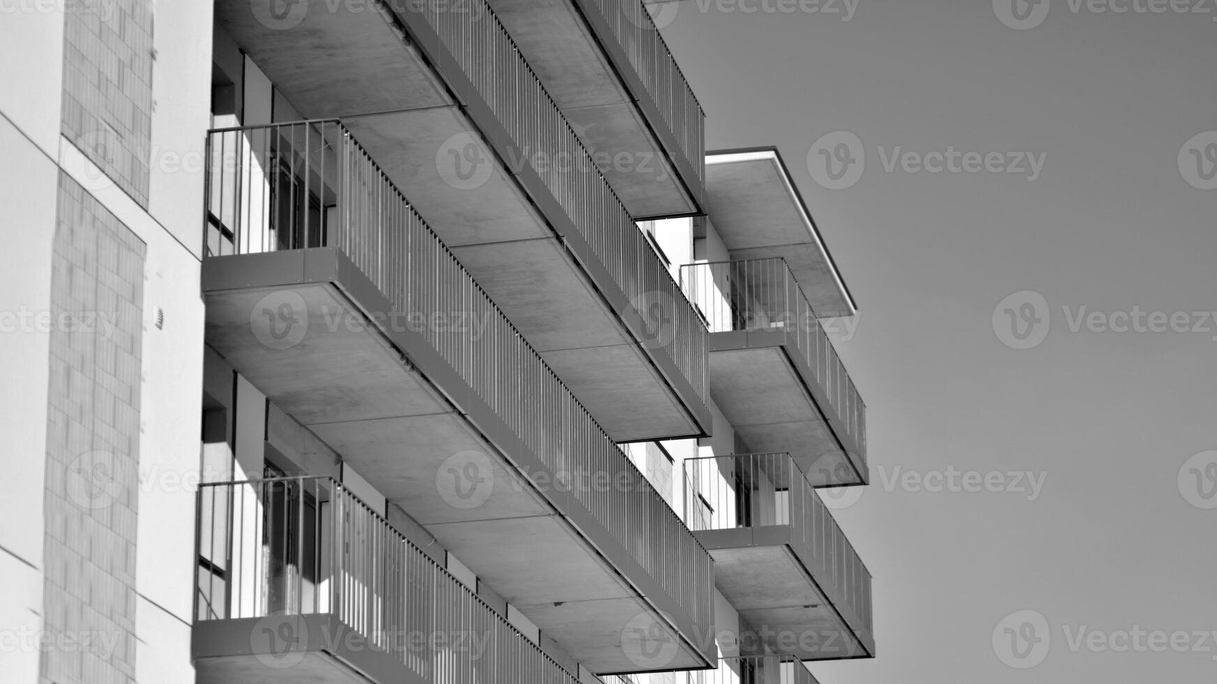 Fragment of the building's facade with windows and balconies. Modern apartment buildings on a sunny day. Facade of a modern residential building. Black and white. photo